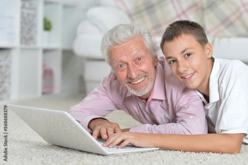 Grandfather with grandson using laptop while lying on floor Grandfather with grandson using laptop while lying on floor