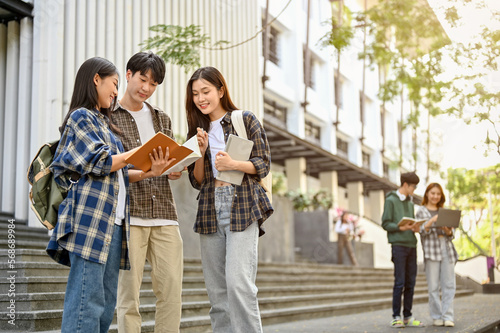 Group of happy Asian college students standing outside of the campus building, talking
