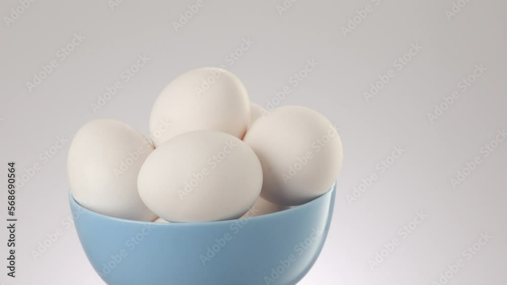 Chicken eggs in a blue bowl moving on a grey background. protein foods. High quality 4k footage Chicken eggs in a blue bowl moving on a grey background. protein foods. High quality 4k footage