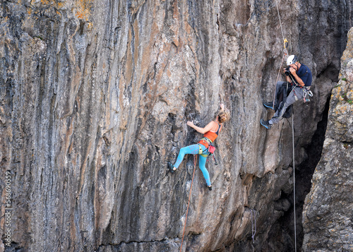 Senior man photographing athlete doing rock climbing