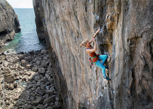 Mature adventurous woman climbing on rocky mountain