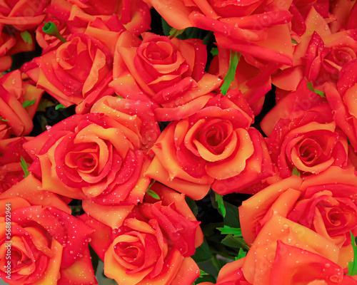 Dark orange artificial handmade roses with water drops bouquet  floral background.