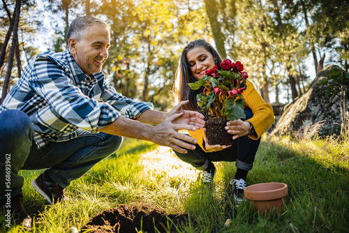 Happy mature couple planting flower in natural garden