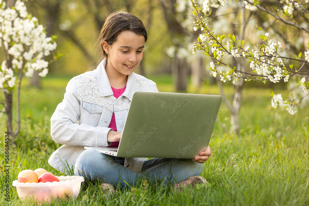 Little girl using laptop computer in a backyard. Child studying at home doing her homework or having online lesson. Homeschooling concept. Little girl using laptop computer in a backyard. Child studying at home doing her homework or having online lesson. Homeschooling concept.