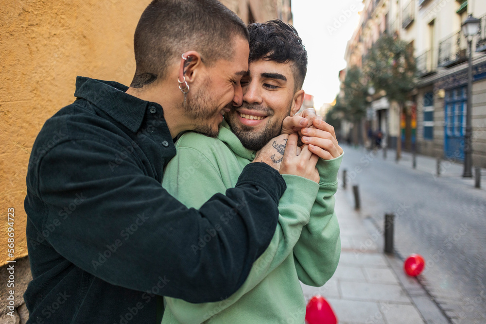 Affectionate gay couple embracing on footpath Affectionate gay couple embracing on footpath