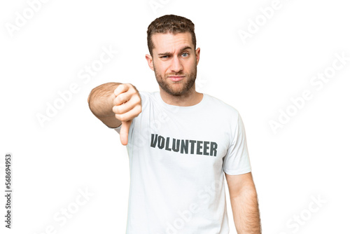 Young volunteer man over isolated chroma key background showing thumb down with negative expression
