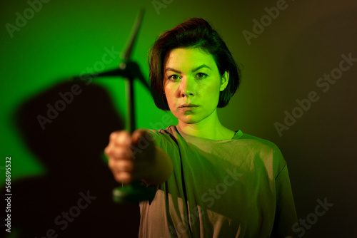 Businesswoman showing wind turbine against colored background