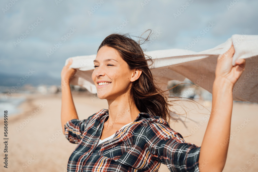 Smiling woman holding scarf and enjoying at beach Smiling woman holding scarf and enjoying at beach