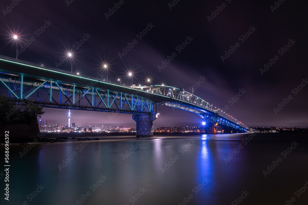 Auckland Harbour Bridge glowing in blue.  Auckland, New Zealand