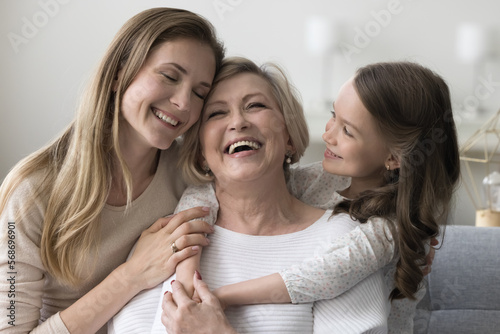 Foto Joyful grandkid girl and adult daughter woman hugging happy excited grandma, cel