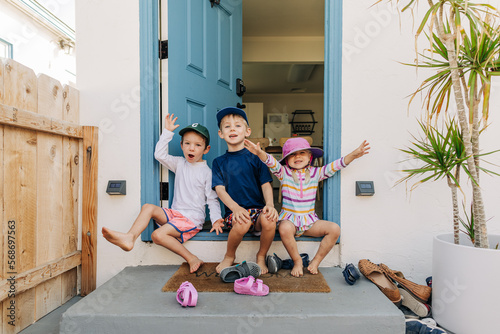 Siblings yell excitedly while sitting on front step of beach house photo