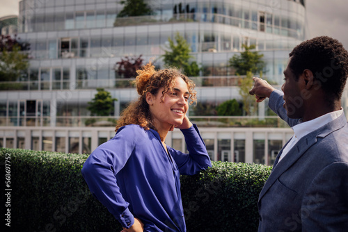 Businessman pointing by colleague leaning on plants