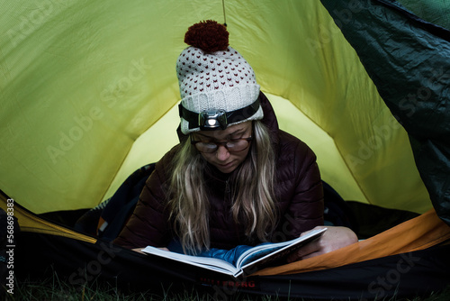 woman reading in her tent at sunset whilst camping solo photo