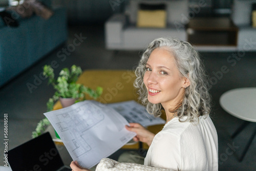 Portrait of smiling achitect holding floor plan in office photo