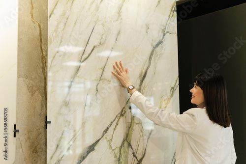 Woman touching marble plate in showroom photo