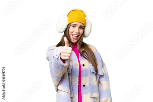 Young woman wearing winter muffs over isolated chroma key background with thumbs up because something good has happened