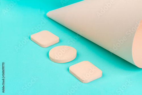 Set of beige makeup sponges on turquoise background. Close up cosmetic powder.