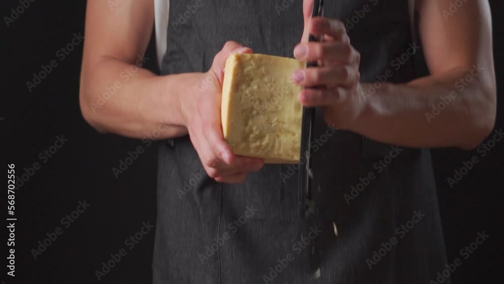 manos rallando queso parmesano con un rallador en camara lenta