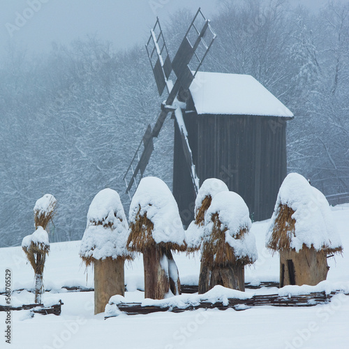 Landscape with wooden mill and hives on the snow.Ukraine,Kiev,Museum of wooden architecture Pirogovo,square