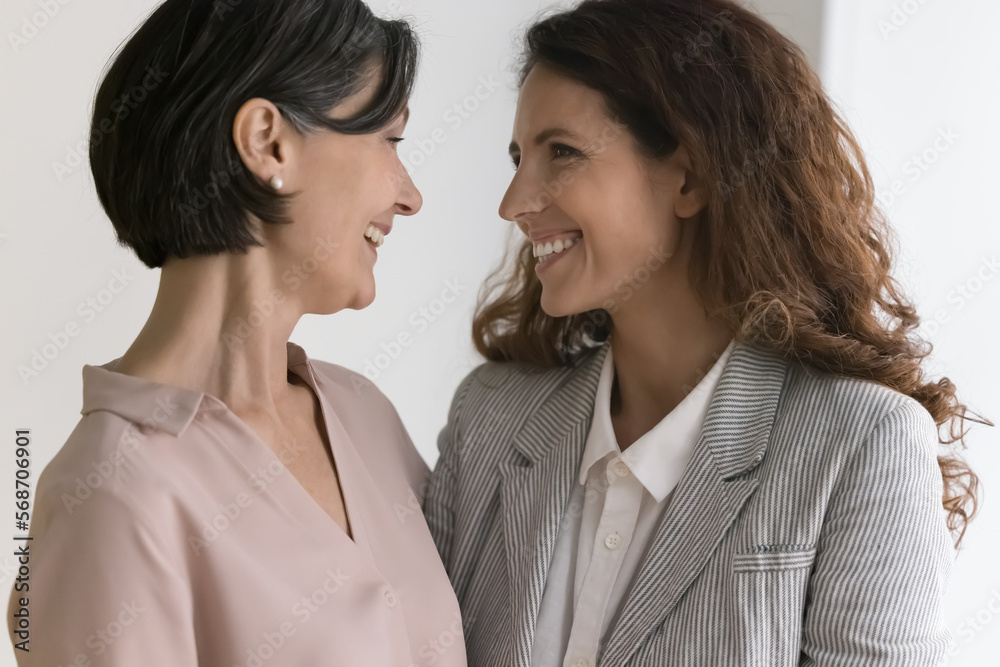 Happy mature mother and adult daughter woman standing close, hugging with love, gratitude, talking, smiling, laughing, discussing good news, enjoying family relationship Happy mature mother and adult daughter woman standing close, hugging with love, gratitude, talking, smiling, laughing, discussing good news, enjoying family relationship