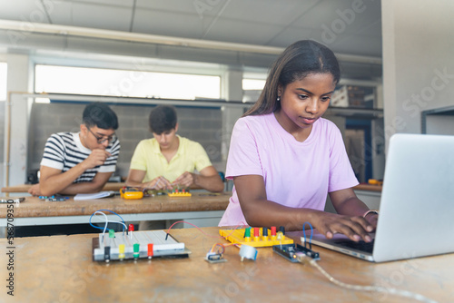 African American High School teenage Student programming electronics circuit board in the science technology workshop - Learning Digital Innovation in Education photo