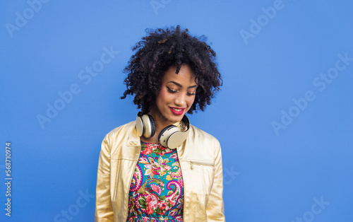 Beautiful black young woman with afro hair style and fashionable clothes strolling in the city