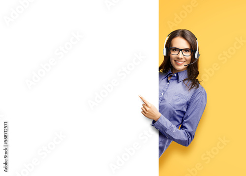 Contact Call Center Service. Customer support, sales agent. Caller answering phone operator. Smiling woman in glasses, headset hold, peep, stand behind white blank signboard, orange yellow background