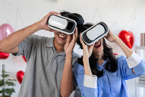 Couple of love playing video games together wearing VR glasses with fun in Valentine's Day concept.