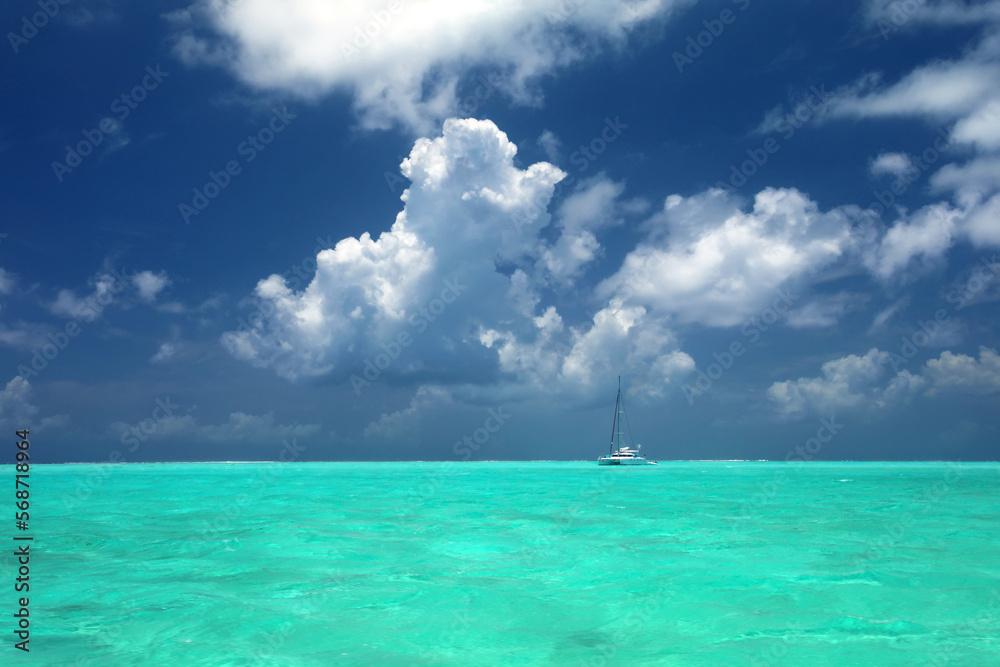 Fototapeta premium Sailing yacht in turquoise ocean at anchor off the beautiful tropical island of Bora Bora, French Polynesia.