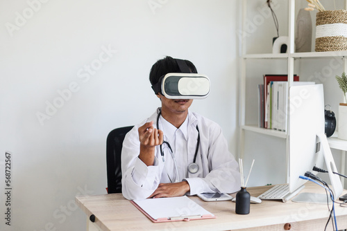 Young doctor wearing VR glasses is sitting and gesturing hands explaining, online medical learning. 