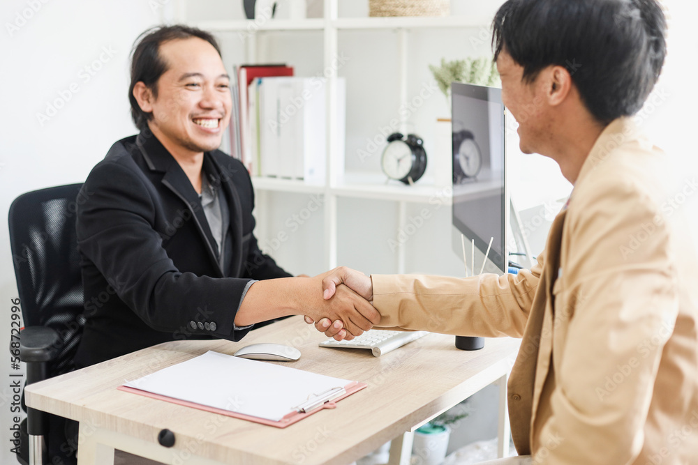 Smiling young businessman hand shaking with his partner after dealing project at the office. Smiling young businessman hand shaking with his partner after dealing project at the office.