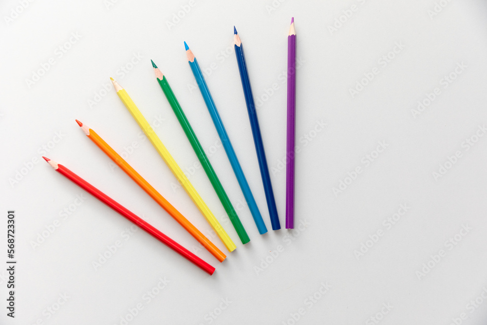 Top view Minimal design of open Notebook with colored pencils of rainbow colors on white background with blank space. Flat lay