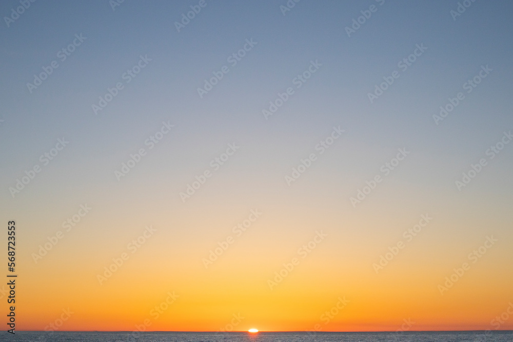 Naklejka premium Orange sun setting over lake