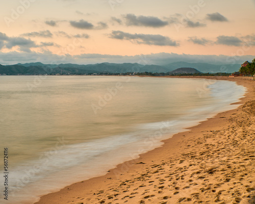 sunset on the beach and the sun is setting on the horizon