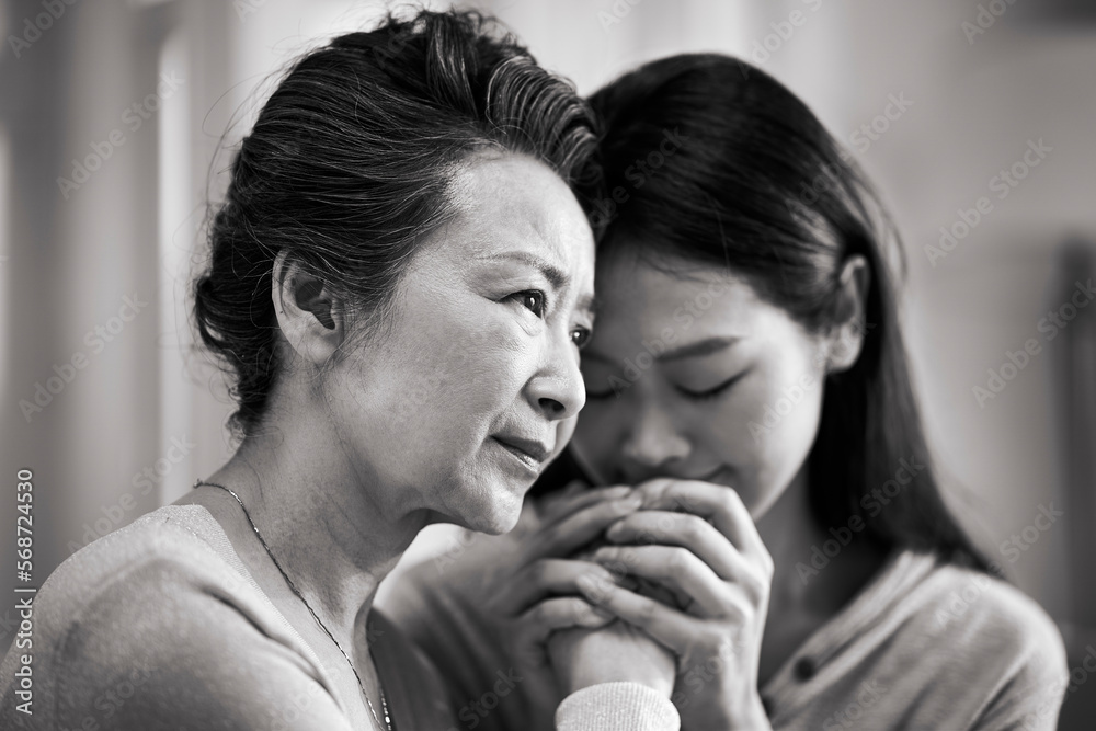 young asian daughter comforting elderly mother young asian daughter comforting elderly mother