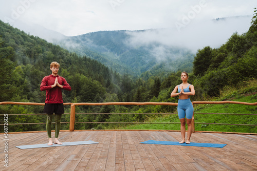 Athletic couple making namaste gesture during yoga practice on terrace in mountains © Drobot Dean