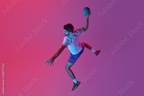 Top view. In a jump. Young man, professional handball player training, playing isolated over gradient pink background in neon light. Winner. Concept of sport, action, championship, sportive lifestyle © master1305