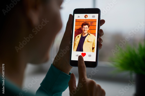 Canvastavla Portrait of a smiling young woman putting red heart button giving like to a cheerful handsome man on her mobile dating application