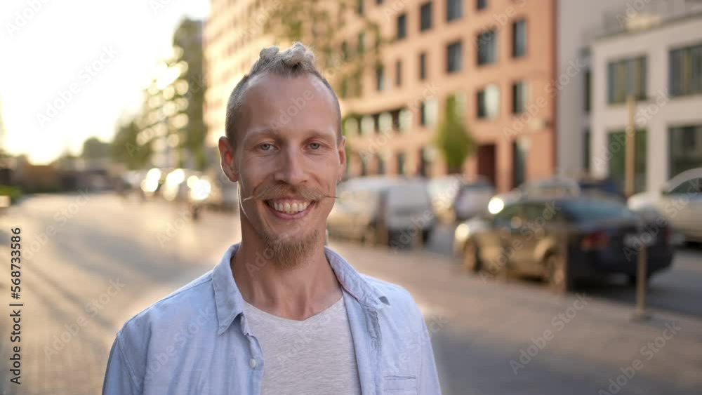 Portrait of young handsome smiling Caucasian guy hipster crazy man with moustache dreadlocks looking at camera at city street. Male guy tourist travel face Expression, surprised human emotion people 