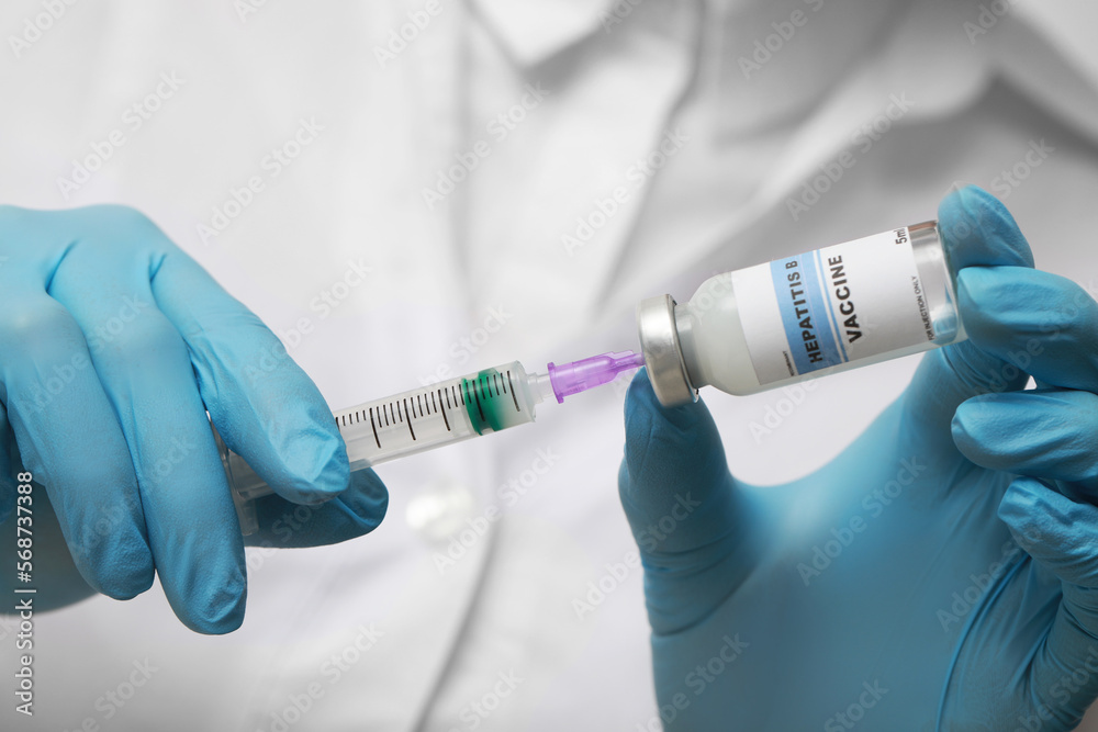 Obraz premium Doctor filling syringe with hepatitis vaccine from glass vial, closeup