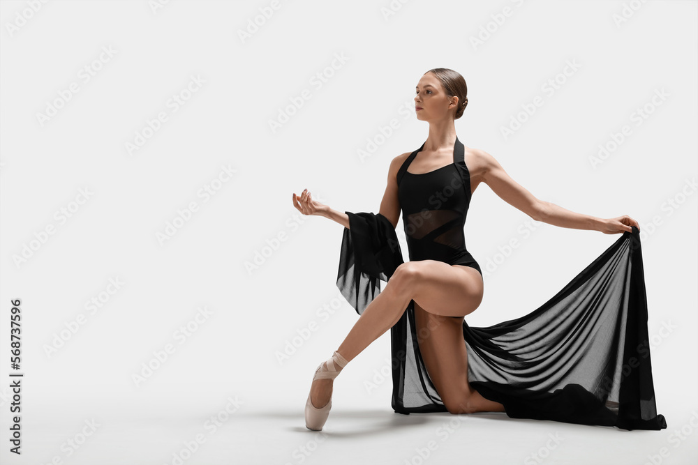 Graceful young ballerina practicing dance moves with black veil on white background. Space for text