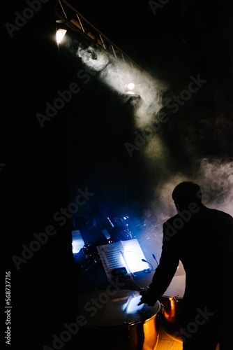 The drummer of a musical band enveloped in smoke during a concert in a theatre.