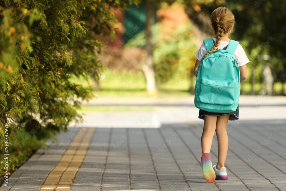 Little girl with backpack going to school, back view. Space for text