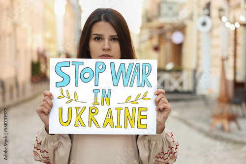 Sad woman holding poster Stop War in Ukraine on city street © New Africa