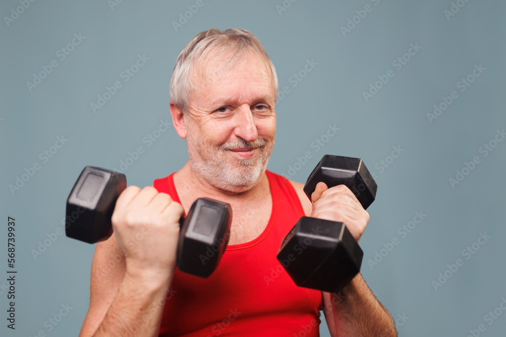 Athletic Pensioner Poses with Dumbbells in Blue Studio Athletic Pensioner Poses with Dumbbells in Blue Studio