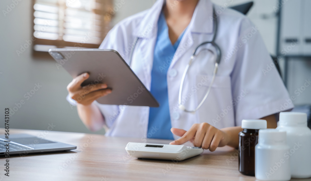 Doctor hold tablet, conduct financial transactions with calculate expenses - income and data documents, put on the desk in the morning. Doctor hold tablet, conduct financial transactions with calculate expenses - income and data documents, put on the desk in the morning.