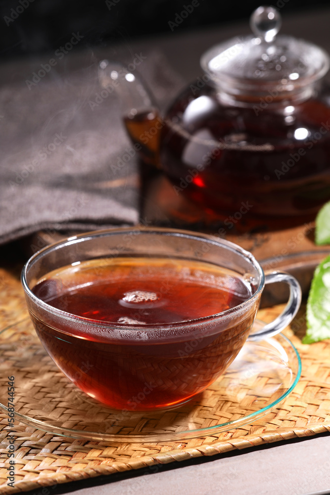 Aromatic hot tea in glass cup and teapot on table Aromatic hot tea in glass cup and teapot on table