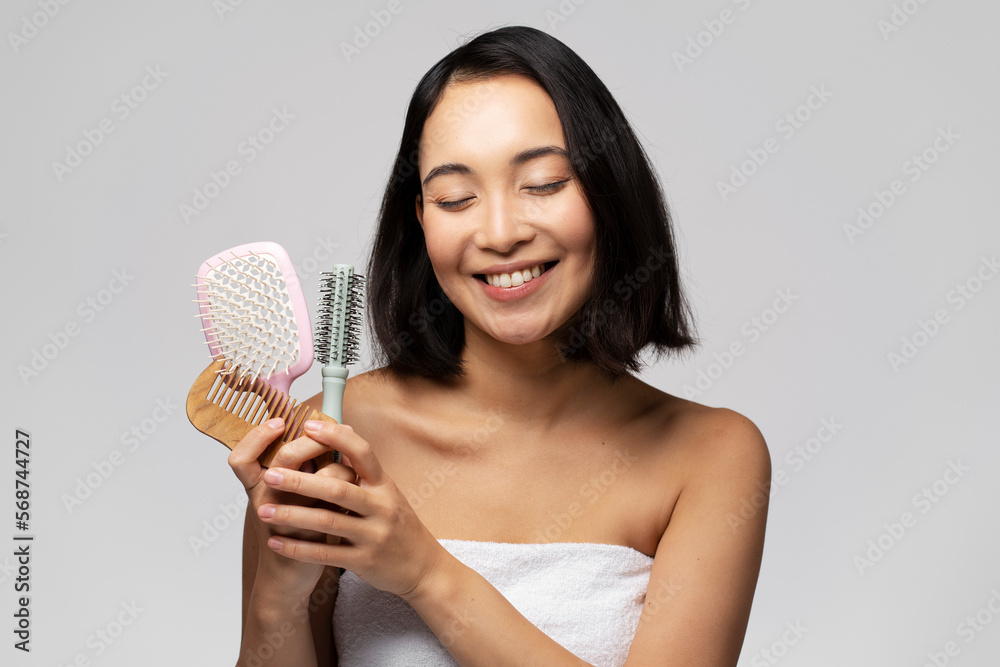 Portrait of positive brunette woman holding hair brushes and posing Portrait of positive brunette woman holding hair brushes and posing