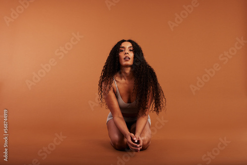 Young black with woman sitting in underwear on an orange background