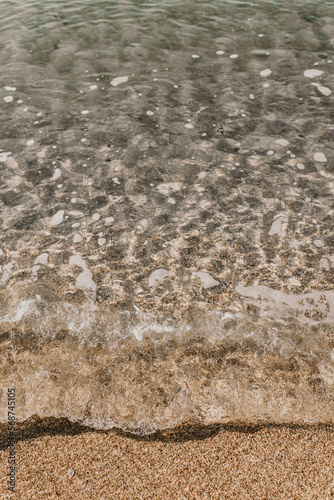 Vertical closeup image of pure transparent water of tide wave with sandy bottom of sea shore. Traveling and adventures concept. Summer vacations on coastline with warm mild climate. No people